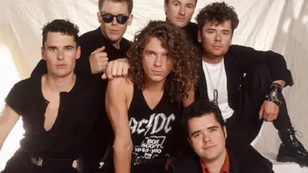 I membri degli INXS posano insieme, un gruppo di sei uomini con stili diversi, pronti a conquistare il mondo con la loro musica.