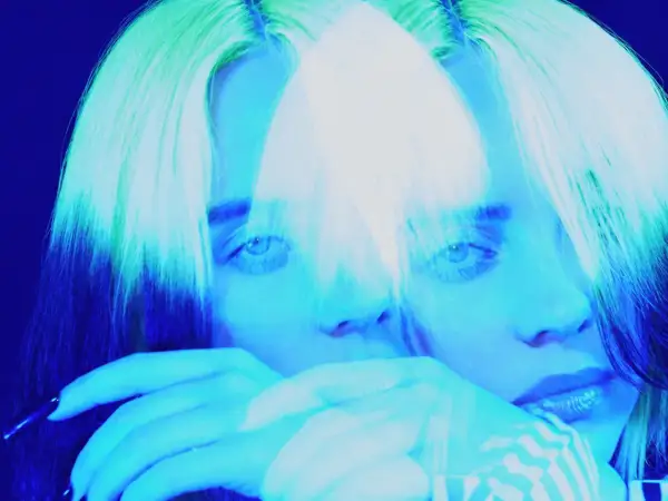 Billie Eilish, icona del pop alternativo, con capelli verdi e blu, in un'immagine surreale che evoca il suo genere musicale unico.