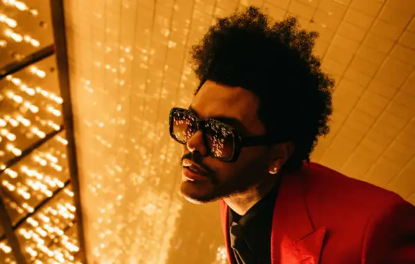 The Weeknd, con occhiali oversize e giacca rossa, pronto per le avventure after hours.