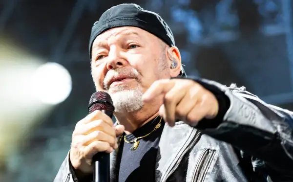 Gerardina trovato, ma non ho più la mia città. Un uomo con berretto nero e giacca di pelle canta al microfono, puntando il dito verso l'esterno.