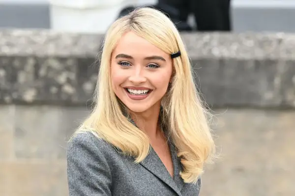 Sabrina Carpenter sorride, con i capelli biondi e un blazer grigio. Ricorda i suoi film e programmi TV.