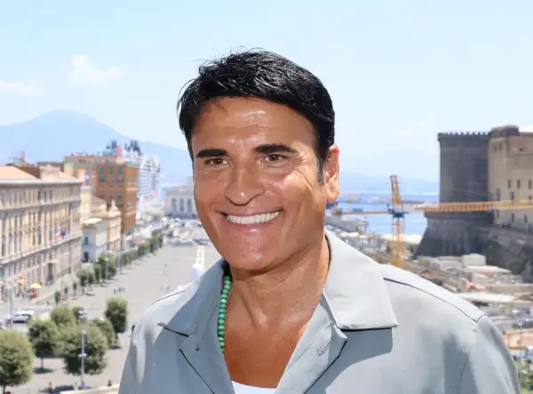 Sorriso di un cantante italiano con Napoli sullo sfondo.