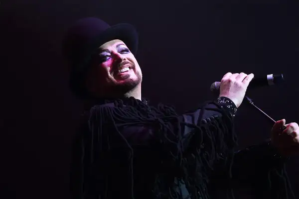 Boy George, icona dei Culture Club, canta con trucco audace e cappello a cilindro.