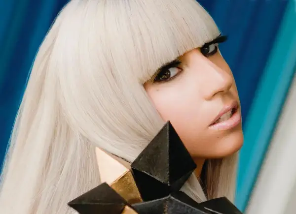 Lady Gaga con i suoi iconici capelli biondi e un look audace, ricorda la sua prima canzone.